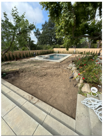 Bare dirt lawn area beside pool before sod installation